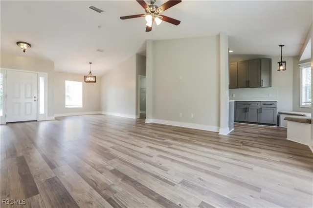 a view of an empty room with a window and wooden floor