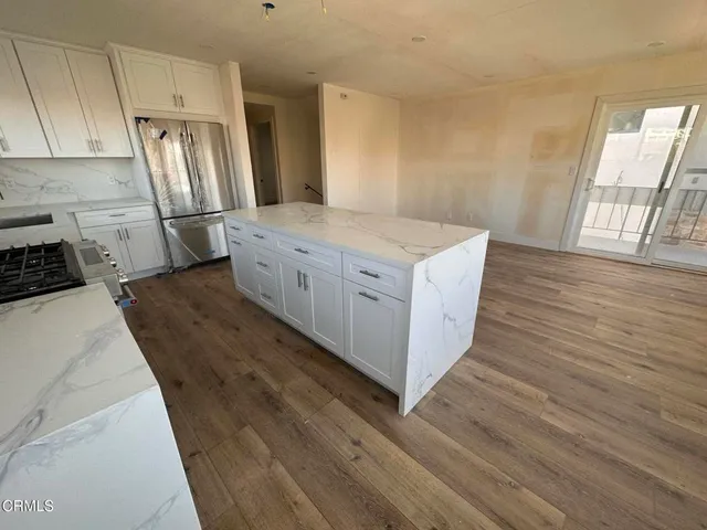 a kitchen with stainless steel appliances granite countertop a stove a refrigerator a sink and wooden floors