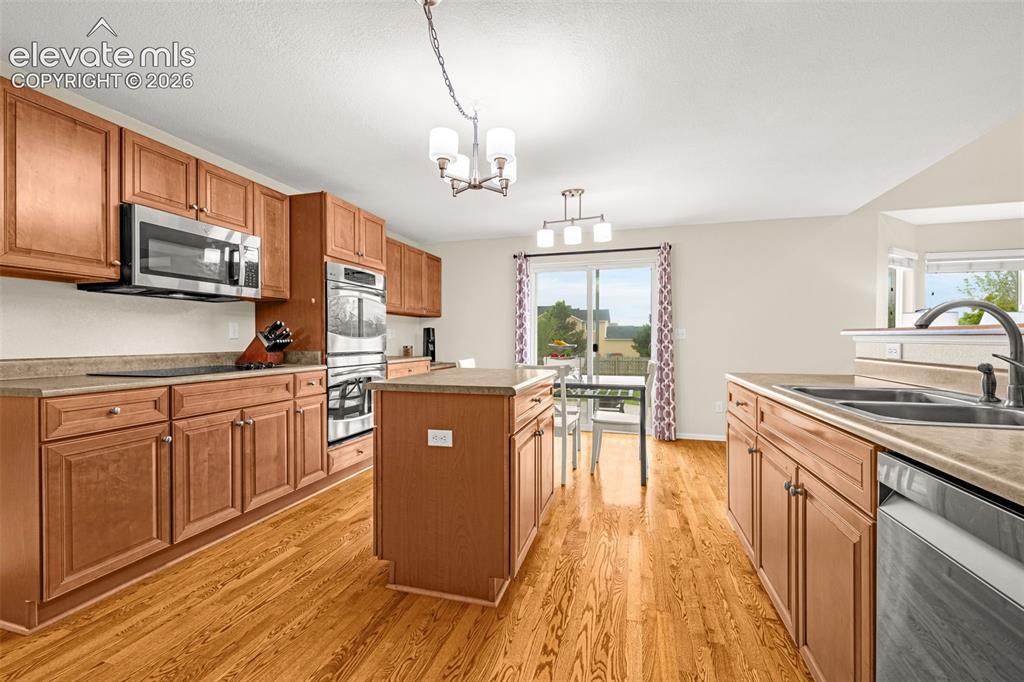 9127 Oakmont Road Peyton, CO 80831 - Photo 8 of 49 a kitchen with stainless steel appliances granite countertop wooden cabinets a stove top oven a sink and dishwasher a oven with wooden floor