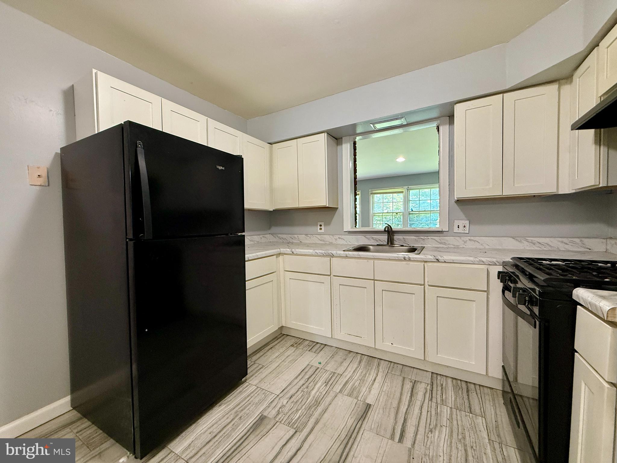701 Harrison Street Riverside, NJ 08075 - Photo 10 of 26 a kitchen with a refrigerator and white cabinets