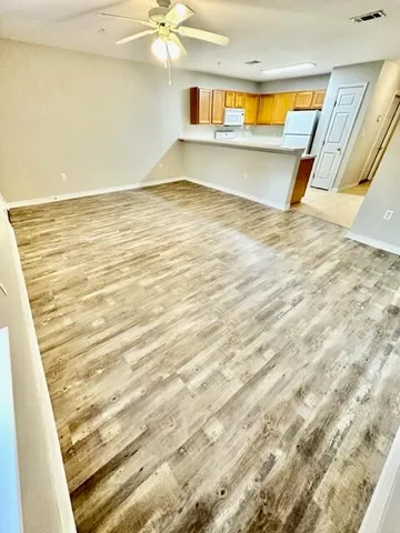 a view of an empty room with wooden floor and a chandelier
