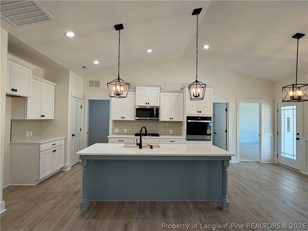 1788 Alderman Mill Road Dunn, NC 28334 - Photo 5 of 14 a large kitchen with stainless steel appliances kitchen island a large counter top a sink a refrigerator and a fireplace
