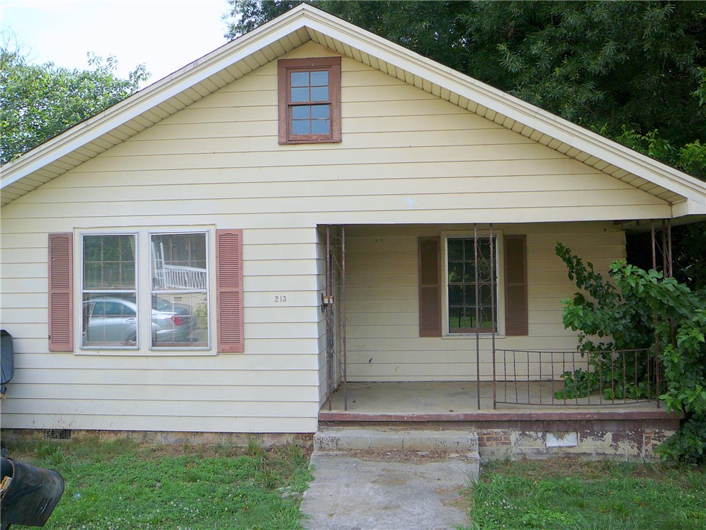 A charming cottage facade featuring a welcoming porch and classic shuttered windows.