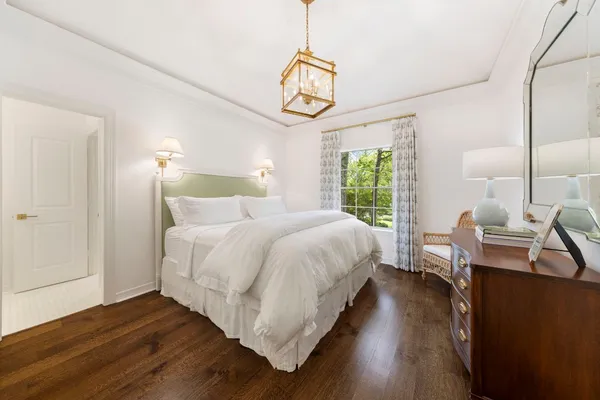 a bedroom with a bed a chandelier and wooden floor