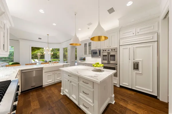 a kitchen with stainless steel appliances granite countertop a white cabinets and wooden floors