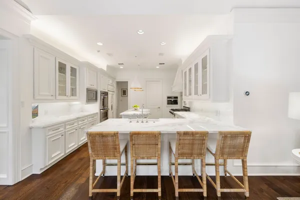 a kitchen with kitchen island granite countertop a dining table chairs and white cabinets