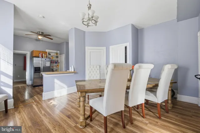 a kitchen with stainless steel appliances granite countertop a refrigerator a sink dishwasher a dining table and chairs with wooden floor