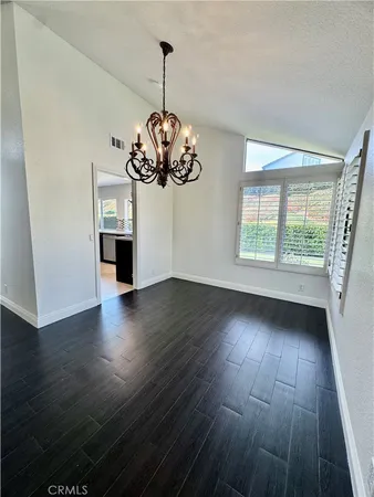 a view of a room with wooden floor chandelier and windows