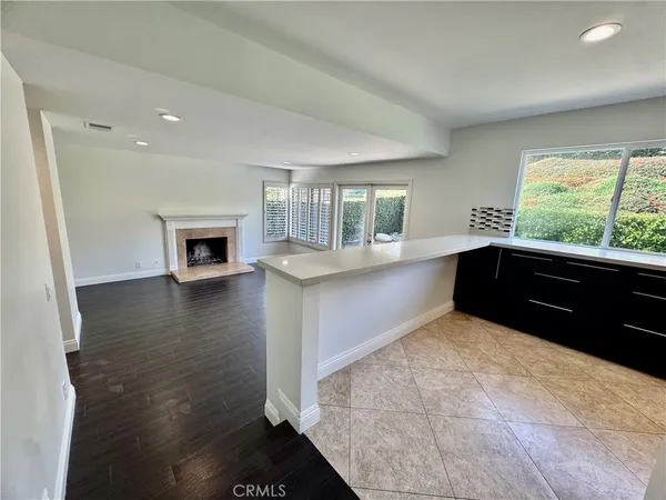 a large white kitchen with granite countertop a stove a sink and a dishwasher with wooden floor