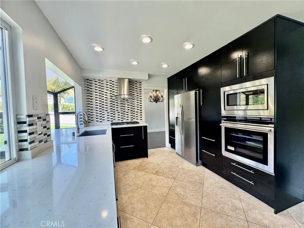a kitchen with stainless steel appliances kitchen island granite countertop a refrigerator and a stove top oven