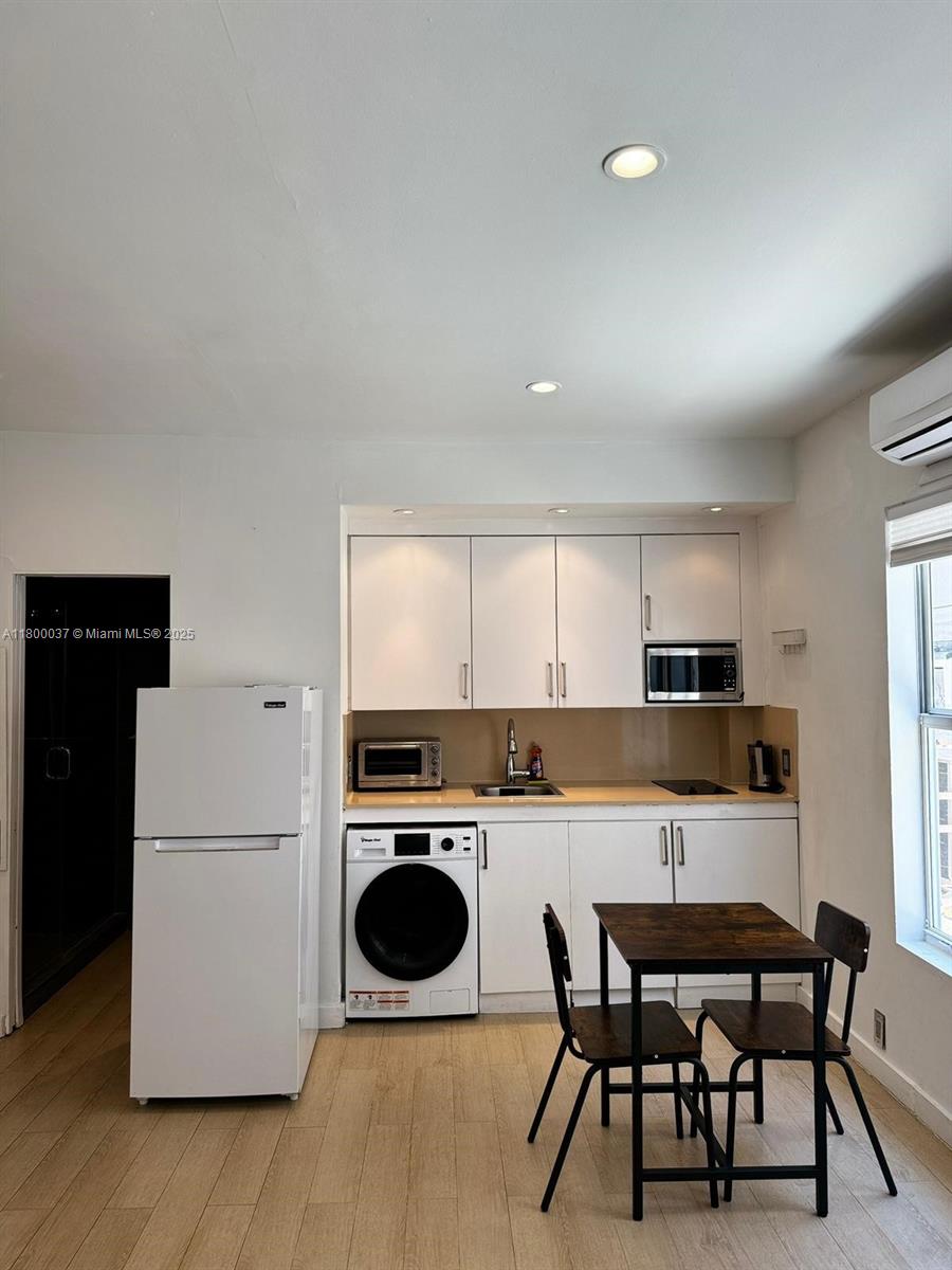 642 Michigan Avenue, Unit 6 Miami Beach, FL 33139 - Photo 2 of 11 a kitchen with a stove a refrigerator and a dining table with wooden floor