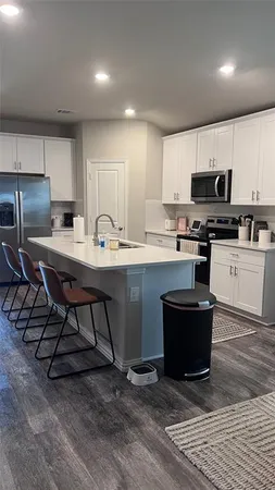 a kitchen with stainless steel appliances a stove a sink a microwave a refrigerator and cabinets