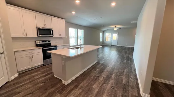 a kitchen with granite countertop a sink wooden floor and a stove top oven