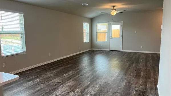 a view of an empty room with a window and wooden floor