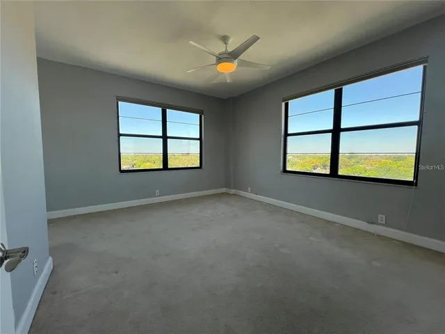 an empty room with windows and ceiling fan