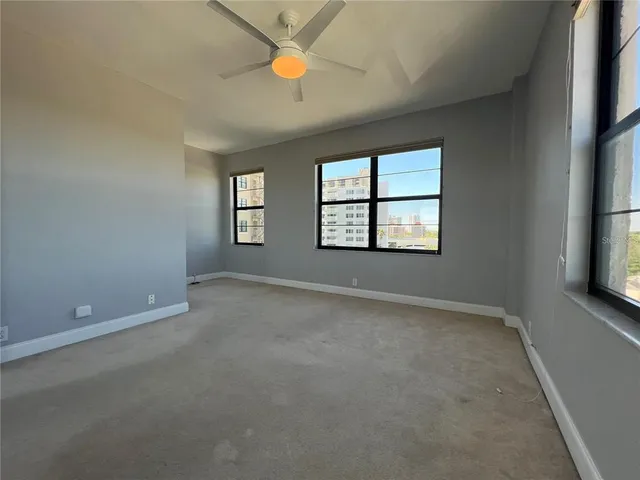 an empty room with windows and fan