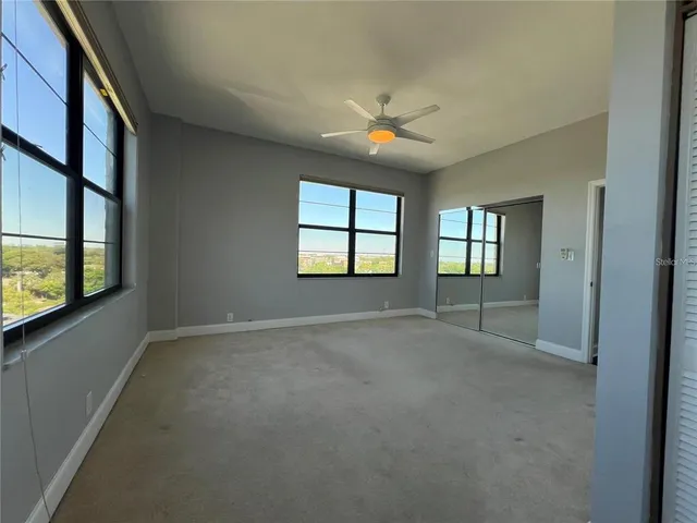 an empty room with windows and chandelier fan
