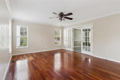 a view of a livingroom with wooden floor a ceiling fan and windows