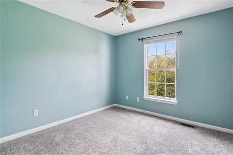 a view of an empty room and chandelier fan