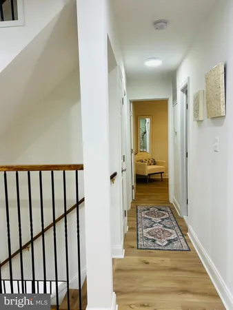 a view of a hallway with a livingroom and wooden floor a bedroom