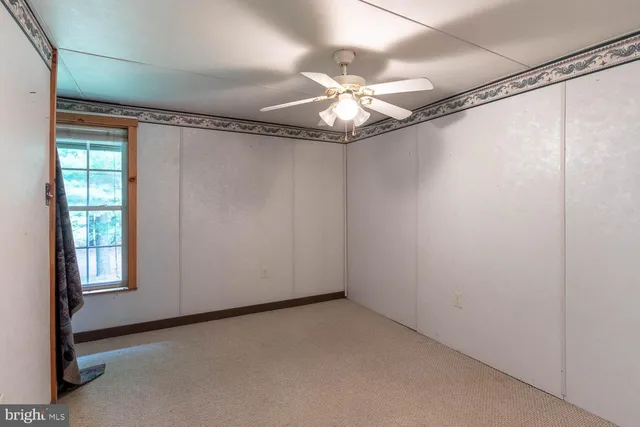 a view of an empty room with chandelier fan and closet