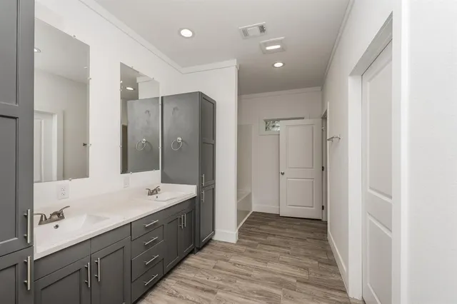 a spacious bathroom with a double vanity sink a large mirror and shower