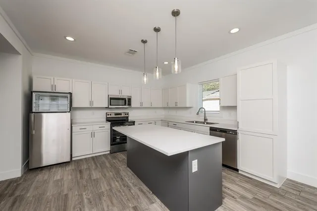 a kitchen with a sink a stove a refrigerator and white cabinets