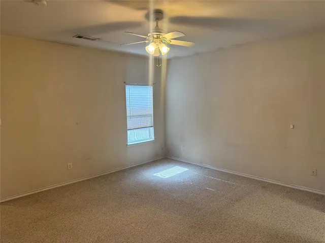 en empty room with windows and chandelier fan