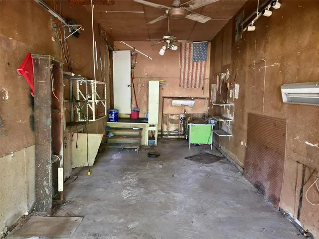 an empty room with a fan & a window