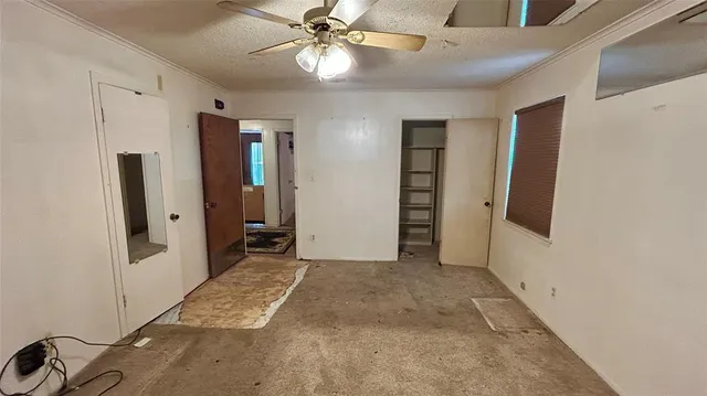 an empty room with closet and a ceiling fan
