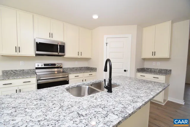 a kitchen with granite countertop a stove a sink and a microwave