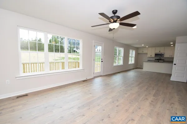 a view of an empty room with a window and a kitchen