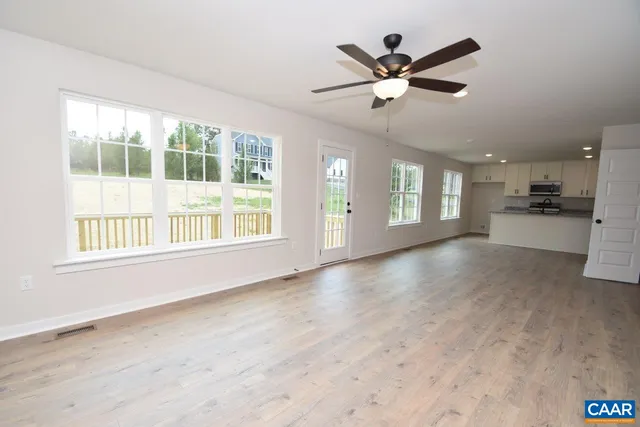 a view of an empty room with a window and a kitchen