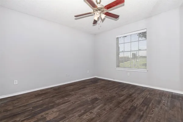 an empty room with wooden floor fan and windows