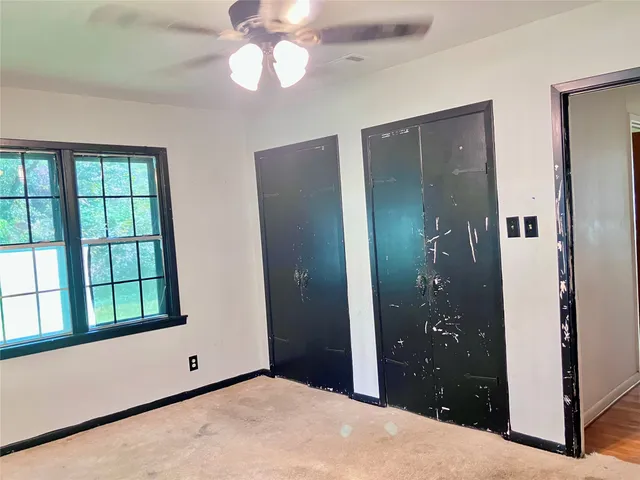 a view of an empty room with a bathroom and a window