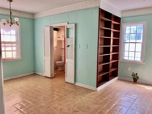 an empty room with closet and windows