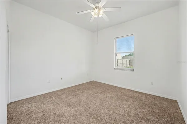 an empty room with a chandelier fan and windows