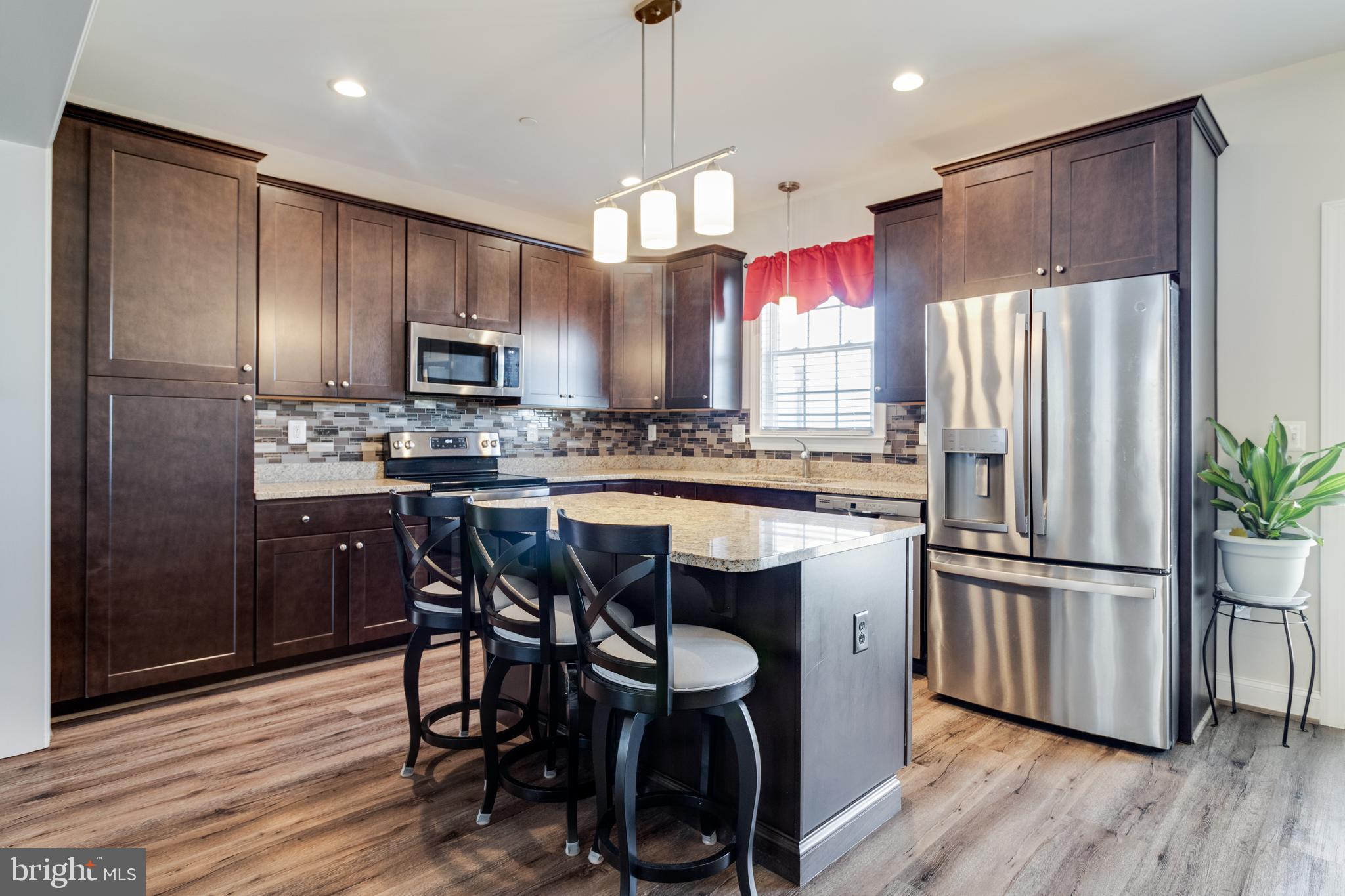 995 Rye Drive La Plata, MD 20646 - Photo 14 of 46 a kitchen with stainless steel appliances a refrigerator a stove a sink dishwasher a dining table and chairs with wooden floor