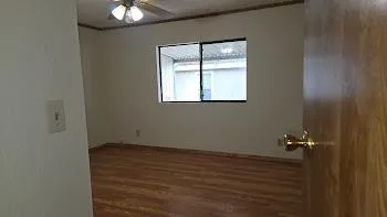 a view of an empty room with wooden floor and a window