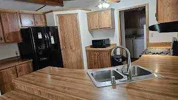 a kitchen with stainless steel appliances granite countertop a refrigerator a stove and a sink with wooden floor