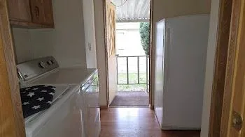 a view of a hallway to a livingroom with wooden floor and windows