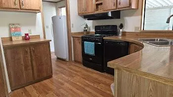a kitchen with stainless steel appliances granite countertop a refrigerator a stove and a sink with wooden floor
