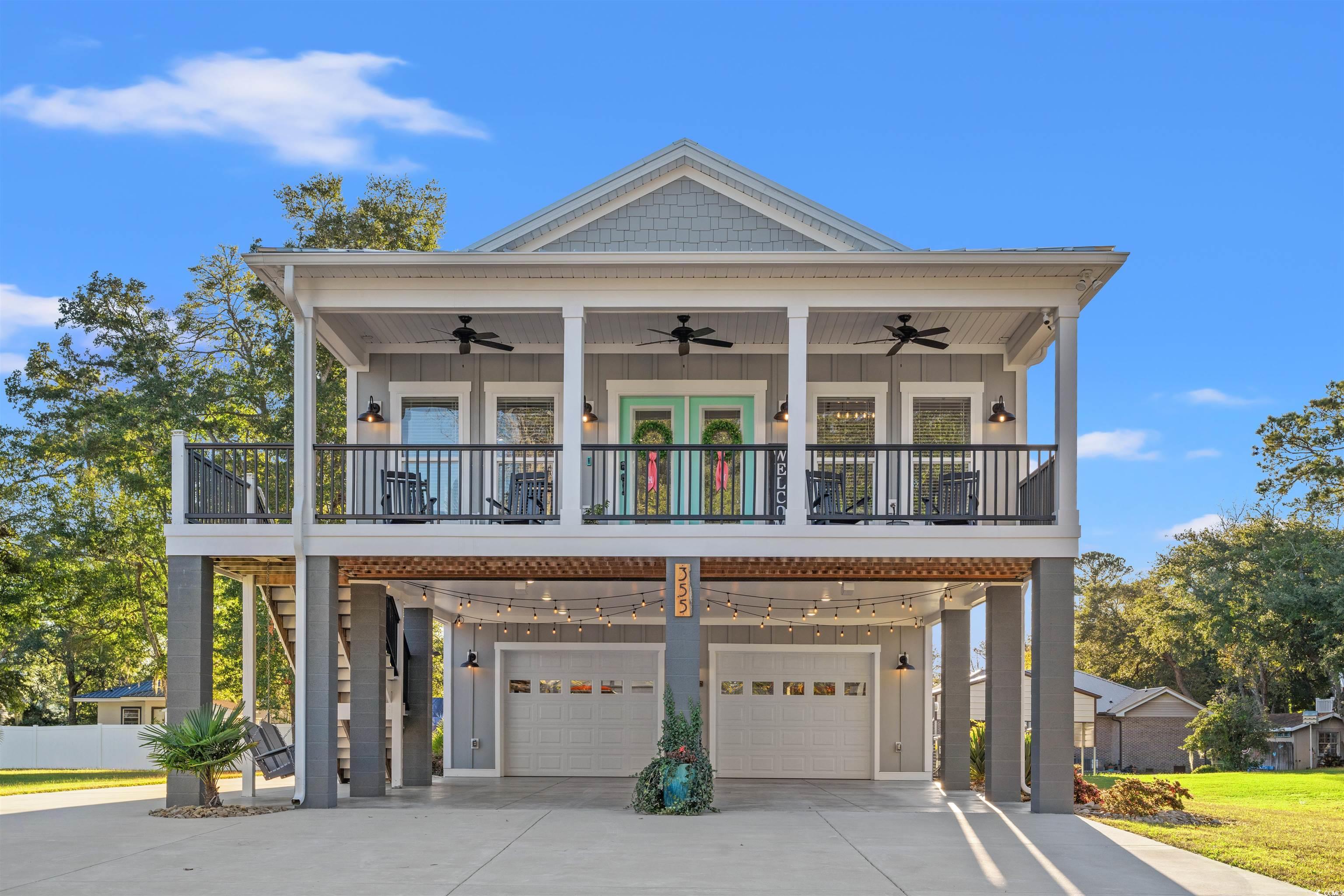 355 Oak Avenue Murrells Inlet, SC 29576 - Photo 2 of 34 View of front of house featuring an attached garage, ceiling fan, board and batten siding, driveway, and a carport