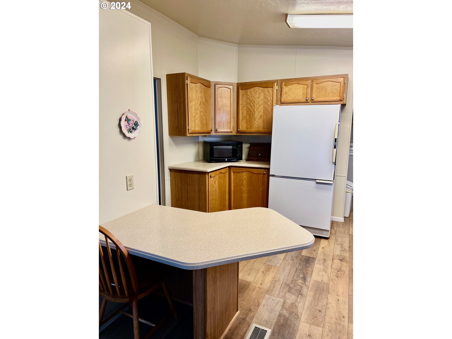 1601 Rhododendron Drive, Unit 694 Florence, OR 97439 - Photo 4 of 32 a kitchen with a table and a refrigerator