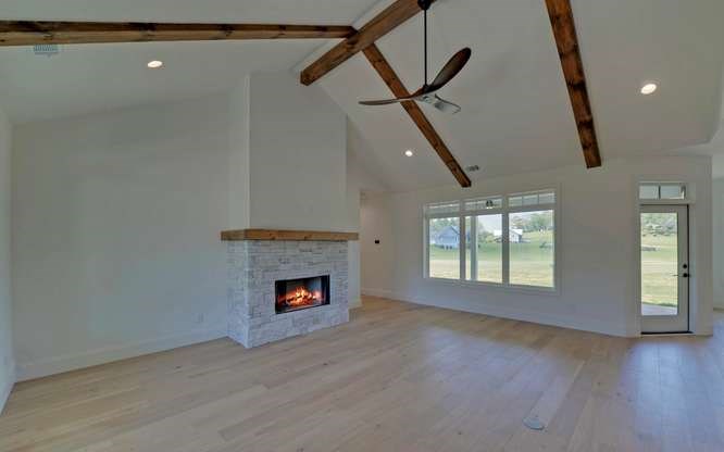 317 Bell Creek Cove Road Hiawassee, GA 30546 - Photo 7 of 74 a view of an empty room with wooden floor fireplace and a window