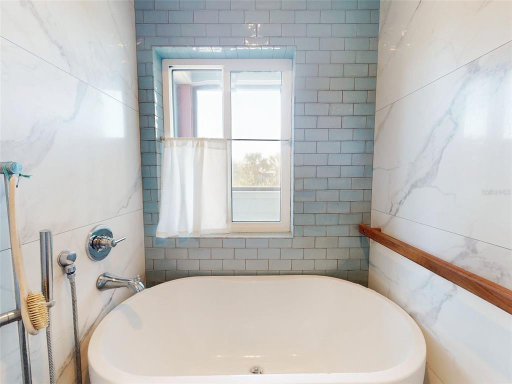 901 Sheepshead Avenue New Smyrna Beach, FL 32169 - Photo 20 of 64 a white bath tub sitting in a bathroom next to a window