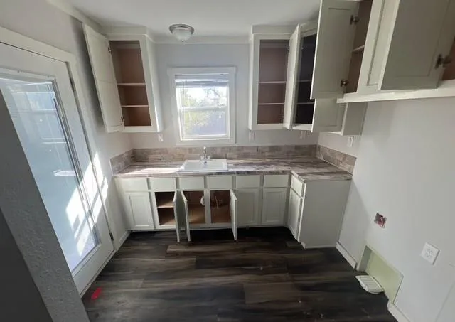 a view of a kitchen with wooden floor and a window