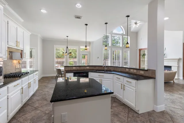 a large kitchen with kitchen island a large counter space a sink stainless steel appliances and windows