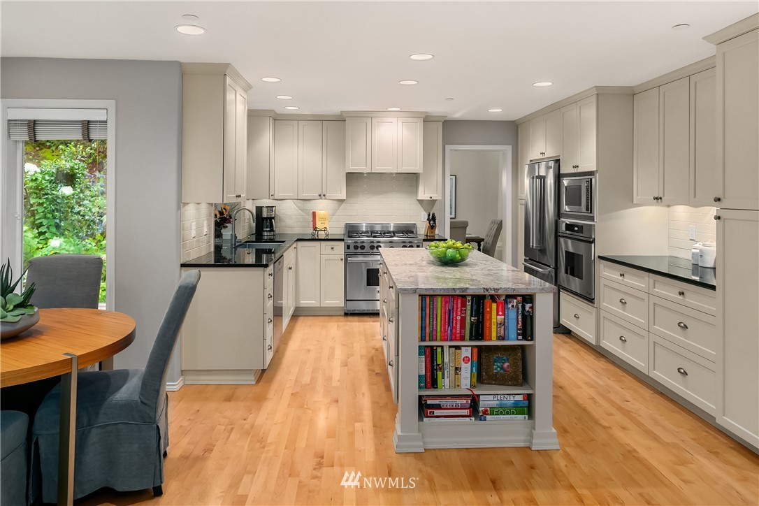 14633 Southeast 82nd Court Newcastle, WA 98059 - Photo 8 of 34 a kitchen with stainless steel appliances granite countertop a refrigerator a stove and a dining table with wooden floor