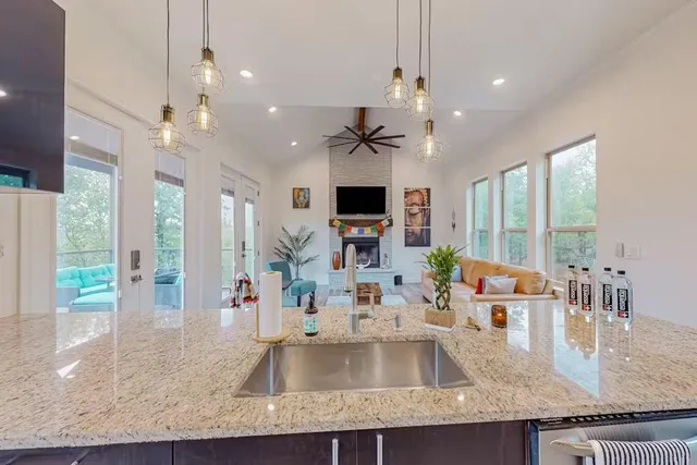 a kitchen with kitchen island granite countertop a sink a counter space appliances and cabinets